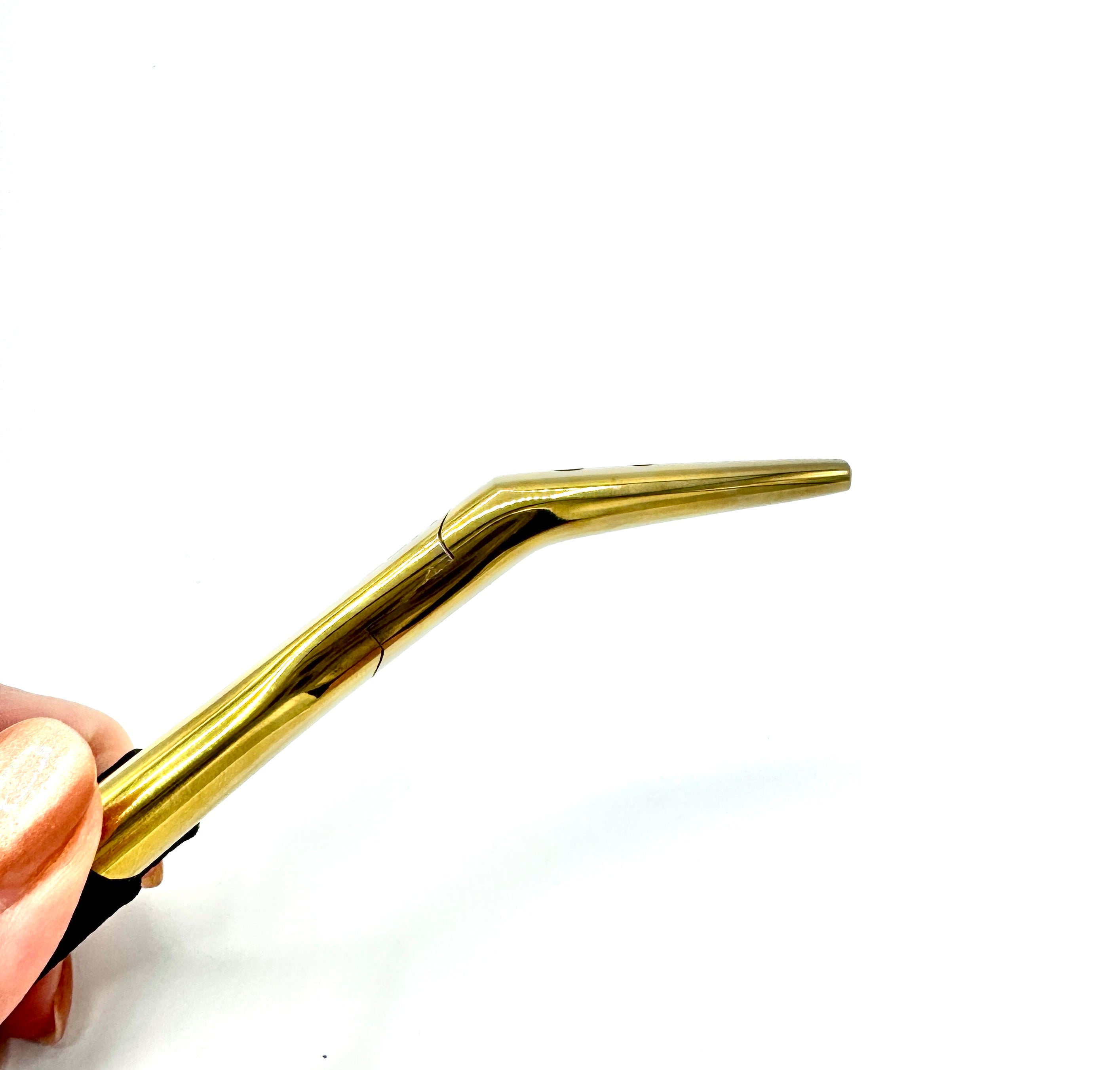Gold-colored eyebrow pencil held by a hand on a white background